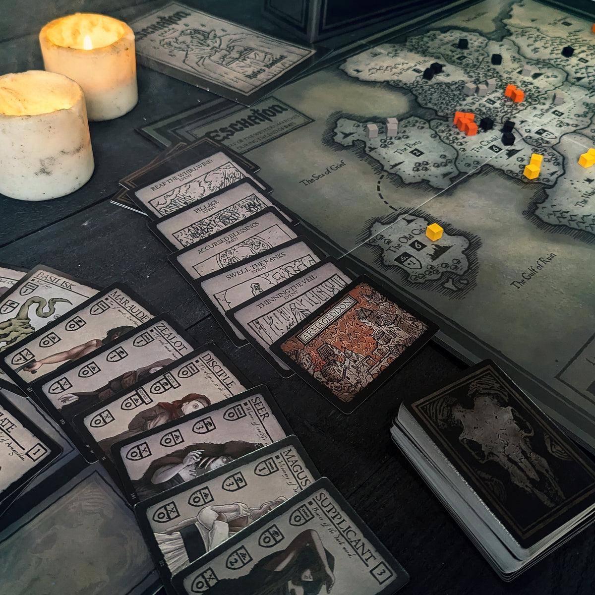 Eschaton event cards and the Armageddon card laid beside the game board, which displays a detailed map of the Accursed Realm.