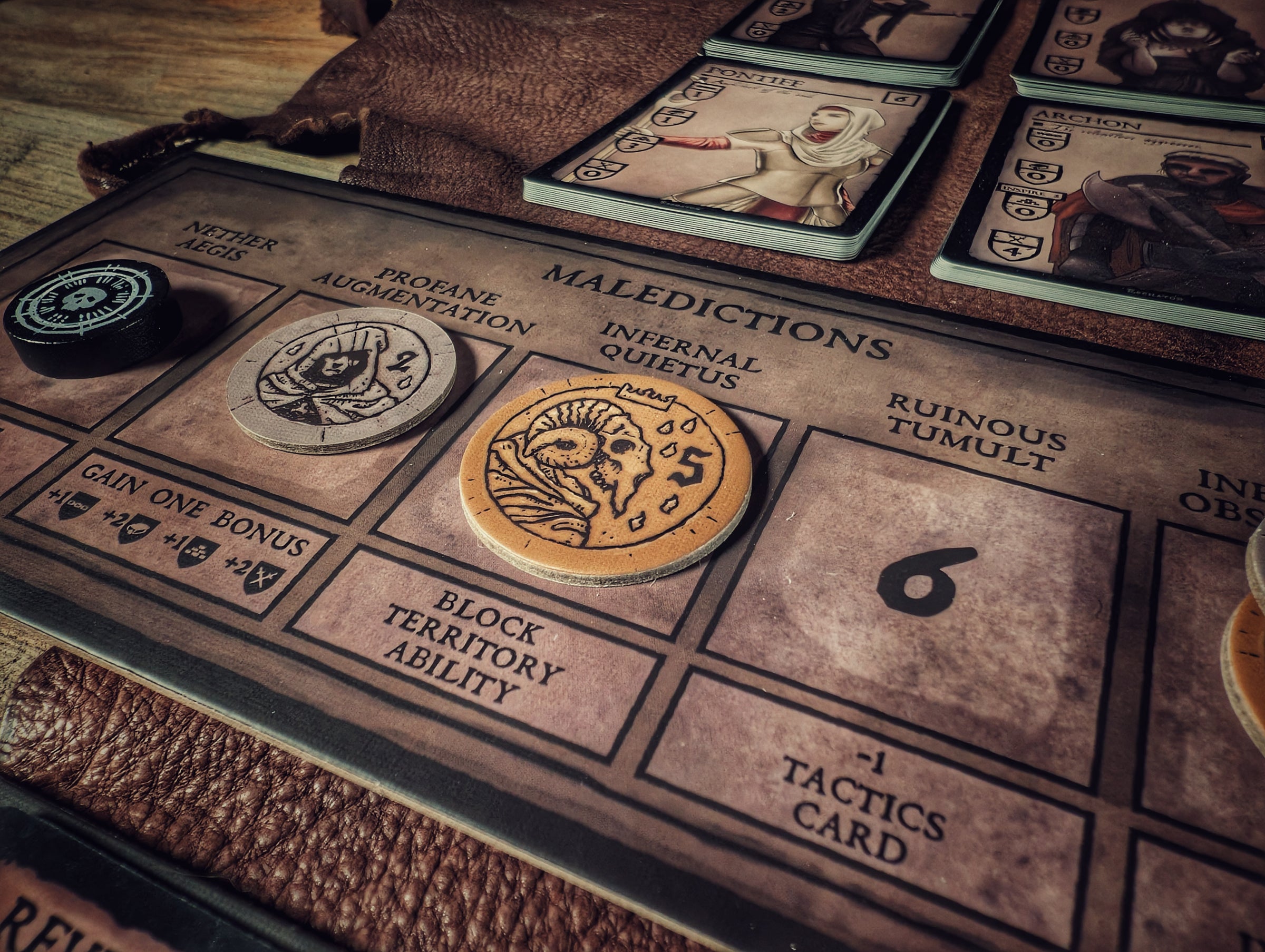 Coin tokens on the cultist malediction playmat for the cult deck-building strategy game.
